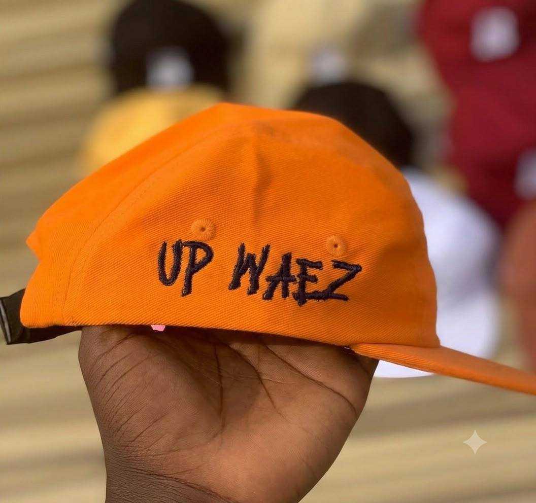 Orange six-panel cap with UP WAEZ embroidered across the front in raised black thread